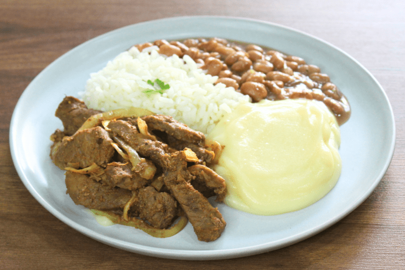 ALCATRA EM TIRAS ACEBOLADA COM ARROZ BRANCO, FEIJÃO E PURÊ DE BATATAS