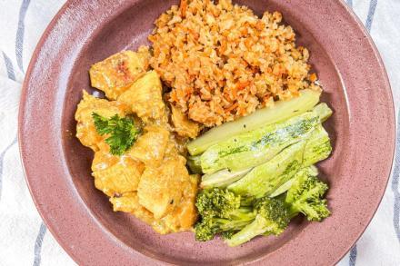 td. Cubos de peito frango marinados em limão e mostarda com cebolas caramelizadas, acompanhado por arroz integral e cenoura, tomate e abóbora ao forno
